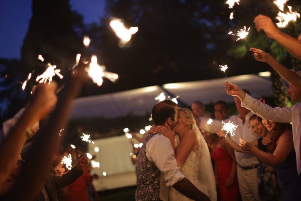 Bride and groom kissing under an arch of sparklers