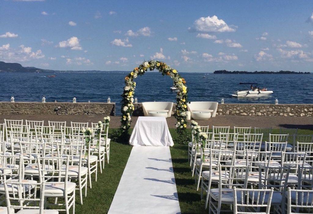 Wedding ceremony set up with a floral arch looking out over Lake Garda
