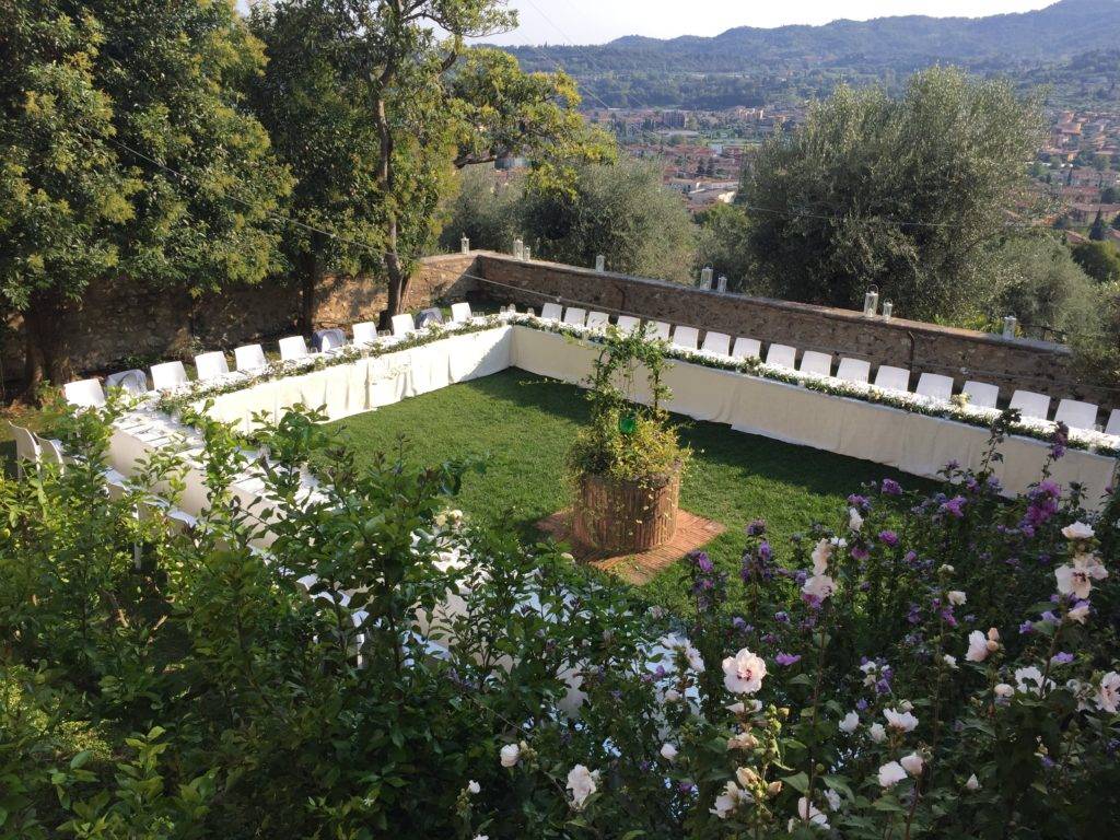 Table laid for a wedding reception in a horse shoe shape in a walled garden in Italy